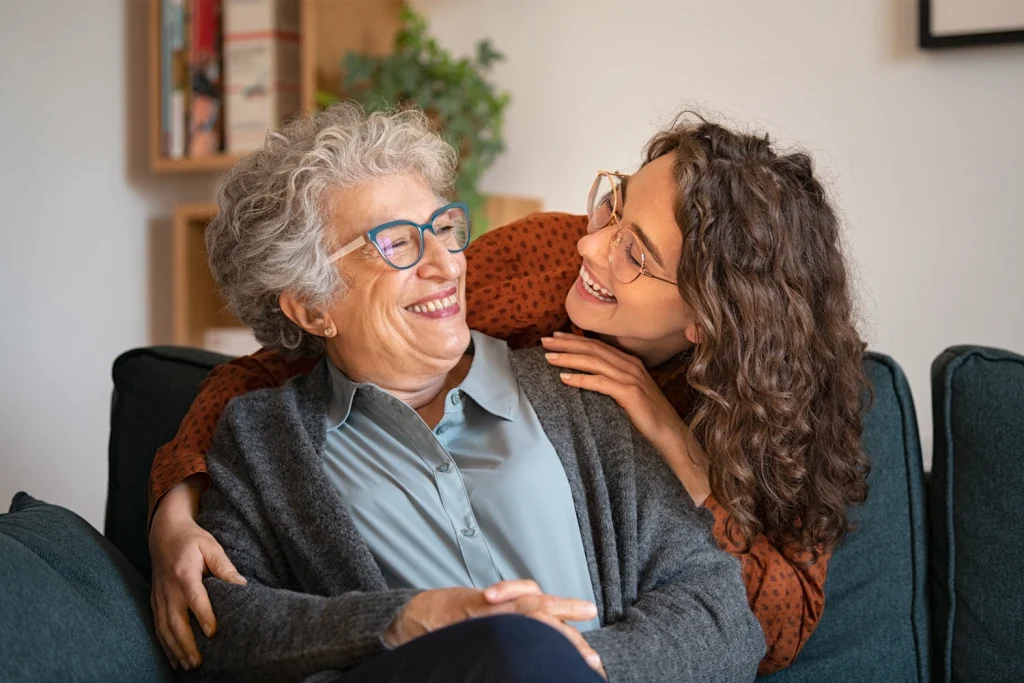 Elderly woman and caretaker laughing and looking at each other